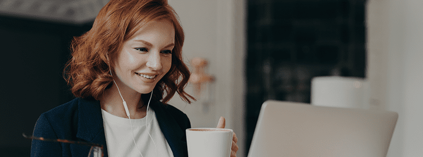 woman drinking a coffee and looking happily on PC