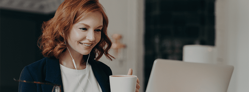 woman drinking a coffee and looking happily on PC