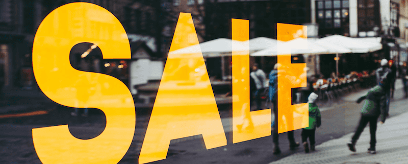 Großer Banner in einem Kaufhaus-Schaufenster, auf dem in gelben Großbuchstaben auf schwarzem Grund "SALE" steht.