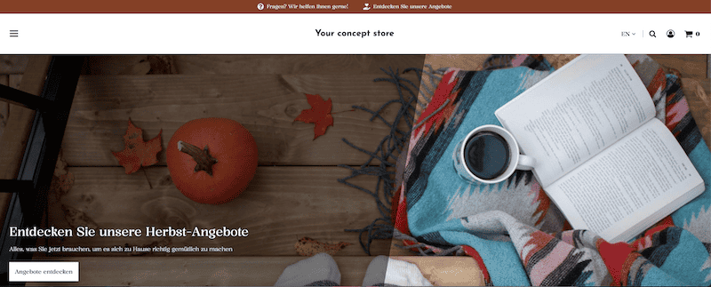 Banner-Bild, das eine herbstliche Atmosphäre zeigt: Jemand steht mit Socken auf einem Holzboden, auf dem ein Hokkaido-Kürbis, einige Herbstblätter sowie eine bunte Decke mit einem Kaffeebecher und einem Buch darauf liegen. Auf dem linken Teil des Bildes ist ein dunkles Overlay mit weißer Schrift und folgender Überschrift: "Entdecken Sie unsere Herbst-Angebote". Text: "Alles, was Sie jetzt brauchen, um es sich zu Hause richtig gemütlich zu machen." Button: "Angebote entdecken".